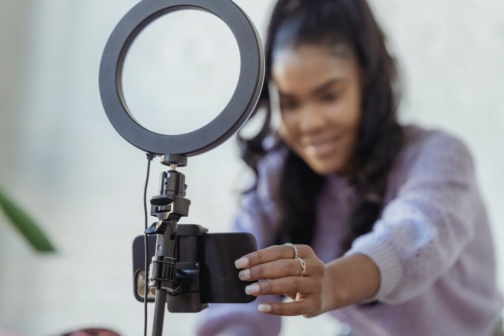 Female content creator adjusting her smartphone on a tripod with a ring light for filming