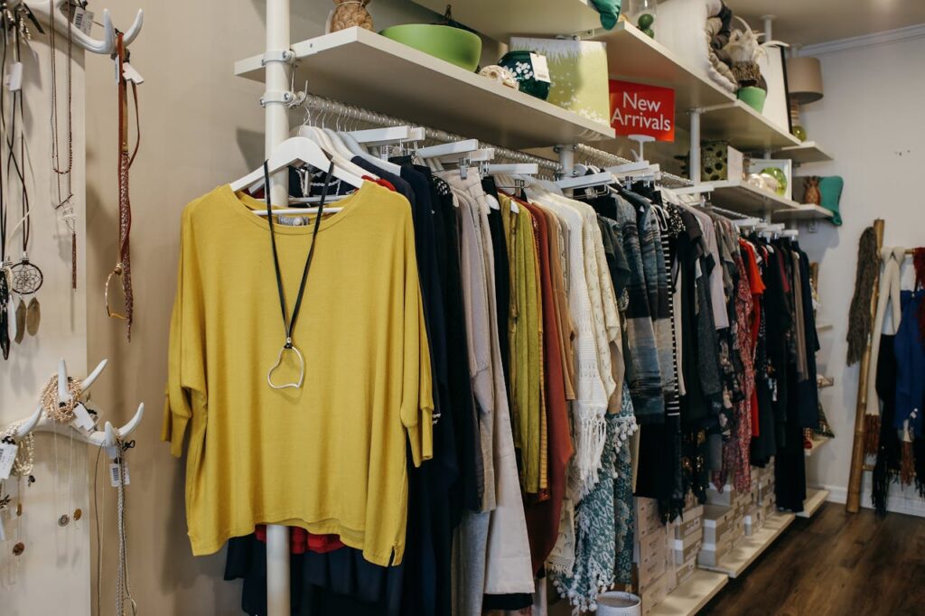 Racks of colorful clothes under a “New Arrivals” sign in a boutique retail store